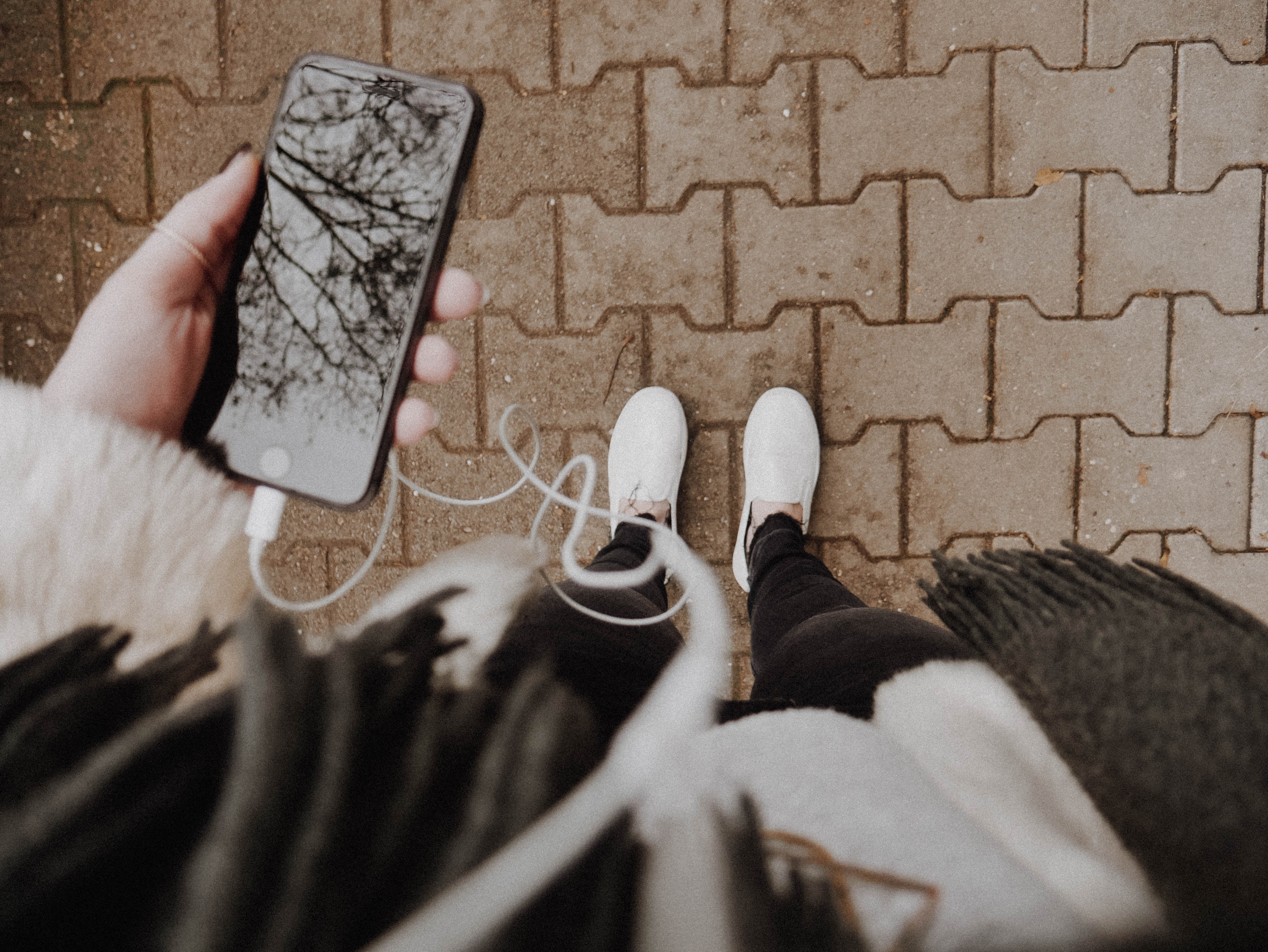 Phone with earphones, looking down towards feet.